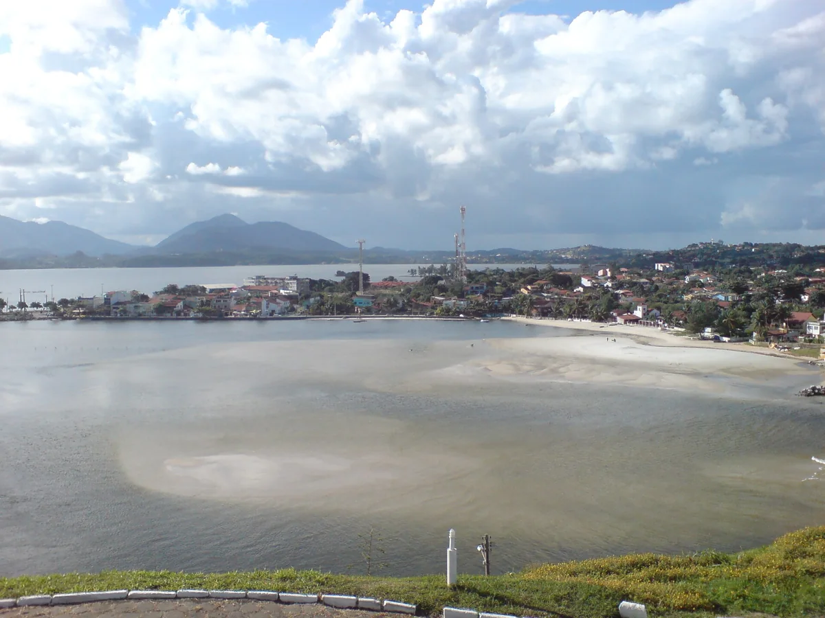 Vista do alto para a Lagoa de Saquarema, com a faixa de areia, a cidade e as serras ao fundo