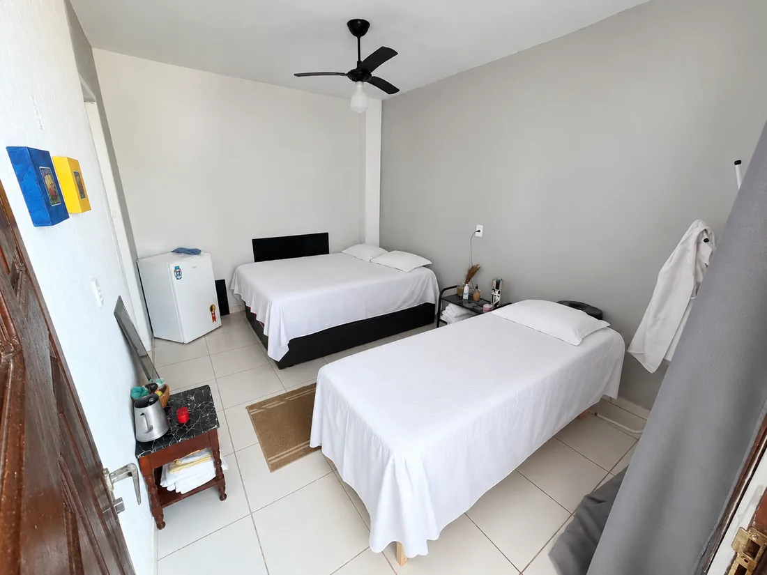 Suíte com cama de casal e cama de solteiro, frigobar e ventilador de teto, com piso claro
